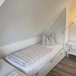 Schlafzimmer mit Dachschrägen, Bett mit Kissen und Nachttisch.