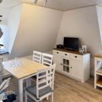 Esszimmer mit Tisch, Stühlen, Fernseher und Küchenmöbeln.