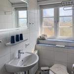 Bathroom with sink, mirror, toilet, and window with windowsill.