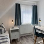 Bedroom with bed, desk, and window with curtains.
