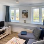 Living room with sofa, TV, and windows overlooking the garden.