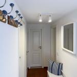 Flur mit Spiegel, Hocker und blau-weißem Kissen. An der Wand hängt ein Kleiderhaken mit blauen Kugeln.