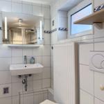 Badezimmer mit Waschbecken, Spiegel, Heizung und Fenster.