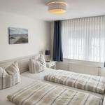 Zwei Betten mit gestreiften Bettwäsche, Fenster mit Vorhängen und Wandbild.