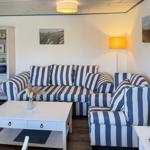 Wohnzimmer mit gestreiftem Sofa, weißen Möbeln und Wandbildern.