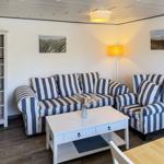 Wohnzimmer mit gestreiftem Sofa, Beistelltisch und Wandbildern