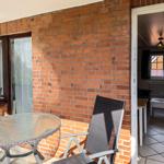 Terrace with table and chairs next to living room with window and radiator.