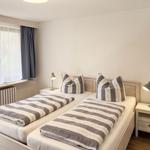Room with two single beds, window, nightstands, and lamps.