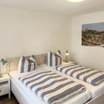 Two single beds with striped covers, nightstands, and wall art with lighthouse.