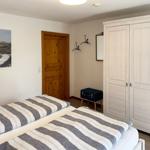 Two beds with striped bedding, white wardrobe, and wooden door.