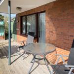 Terrace with table and two chairs, red brick wall, green beach chair in background.