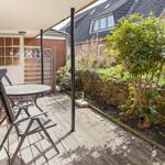 Terrace with table and chairs, surrounded by garden and stone wall.