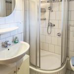 Bathroom with shower, sink, and toilet. White tiles and mirror.