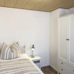 Bedroom with bed, nightstand, and wardrobe. Ceiling with wooden panels.