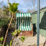 Green beach chair with striped pattern in garden area.