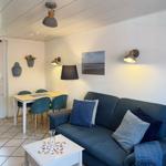 A living and dining area with a sofa, table, chairs, and wall lighting.