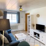 Living room with sofa, TV, and table. Window with curtains and radiator.