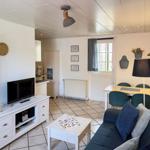 Living area with sofa, dining table, and TV. Kitchen in background. Window with curtains.