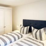 Schlafzimmer mit zwei Betten, dunklem Kopfteil und weißem Schrank.