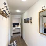 Flur mit Spiegel, Wandbildern und Blick in Schlafzimmer und Küche.