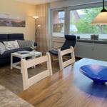 Ein Wohn- und Essbereich mit Sofa, Stühlen und einem blauen Schale auf dem Tisch.