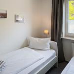 Zimmer mit zwei Betten, Fenster mit Blick auf Bäume und Lampen an der Wand.