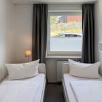 Zwei Einzelbetten, Fenster mit Jalousie und Vorhang, Wandlampe und Bild.