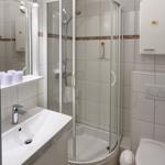 Badezimmer mit Dusche, Waschbecken und Toilette. Weiße Fliesen und Spiegelschrank.