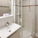 Badezimmer mit Dusche, Waschbecken und Spiegel.