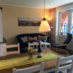 Esszimmer mit Tisch, Stühlen und Sofa. An der Wand hängt ein Strandbild.