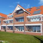 Red brick house with large windows and solar panels on the roof.