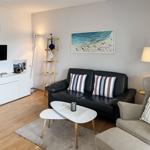 Living room with sofa, armchair, coffee table, and TV mounted on wall.