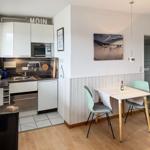 Kitchen with dining area, table with two chairs, wall picture and door