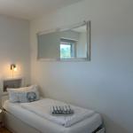 A bedroom with a bed, a mirror, and a lamp.