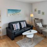 A living room with sofa, armchair, table, and wall art.