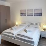 Zimmer mit Doppelbett, Nachttischen und Wandbildern.