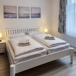 Ein Schlafzimmer mit weißem Bett, zwei Nachttischen und einem Fenster mit Vorhängen.