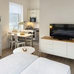 Schlafzimmer mit TV, Küchenbereich und Esstisch. Modern eingerichtet.