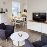 Wohnzimmer mit Essbereich, Küchenzeile und Fernseher auf Schrank