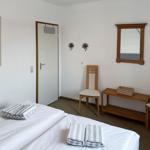 Room with two beds, wooden chairs, mirror, and map on wall.