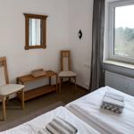 Room with two beds, mirror, chairs, and window with view.