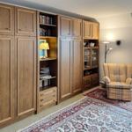Large wooden wardrobe with shelves and seating. Rug and window are visible.