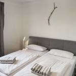 Room with double bed, window, nightstand, and wall decoration.