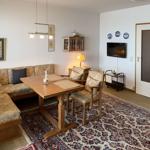 Living and dining area with wooden table, sofa, and TV mounted on the wall.