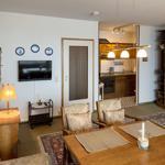 Living and dining area with kitchen. Wooden furniture, TV, and carpeted floor.