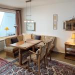 Dining room with wooden table, bench, chairs, rug, and wall art.