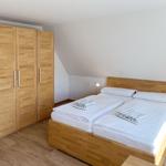 Schlafzimmer mit Holzbett und Kleiderschrank. Zwei Nachttische mit Lampen.