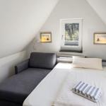 Ein Schlafzimmer mit Dachschräge, Bett und Fenster mit Blick auf Wald.