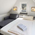 Schlafzimmer mit Bett, Sofa und Fenster mit Blick auf Wald.