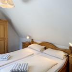 Schlafzimmer mit Doppelbett, Holzmöbel und Nachttischen mit Lampen.